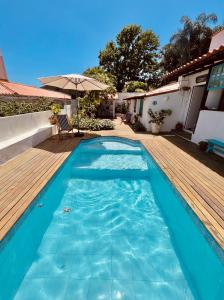 een blauw zwembad met een houten terras en een parasol bij Casa La Buziana in Búzios