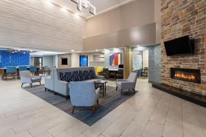 a lobby with a fireplace and chairs and a tv at Holiday Inn Express Harrisburg I-81 - Hershey By IHG in Manadahill