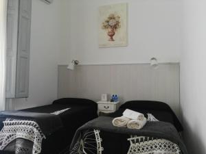 Dos camas en una habitación con toallas. en Hostal Dragonflybcn, en Barcelona