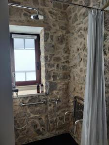 a bathroom with a shower with a stone wall at Casa do Cruzeiro in Ourém