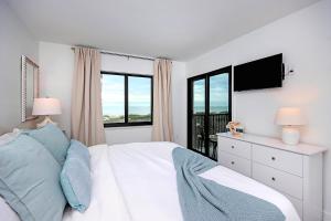 a bedroom with a bed and a tv and windows at Spacious 2BR Condo With Beach Views Sanibel Island 1C2 in Sanibel +24 photos