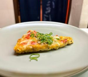 a piece of pizza sitting on a white plate at Yama Lodge Madarao in Madarao Kogen +23 photos