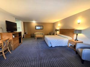 a hotel room with a bed and a flat screen tv at Breeze Inn Hotel in Seward
