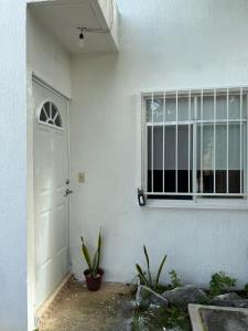een wit huis met een deur en een raam bij Casa Naay in Cancun
