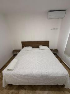 een slaapkamer met een wit bed en 2 tafels bij Casa Naay in Cancun +5 foto's