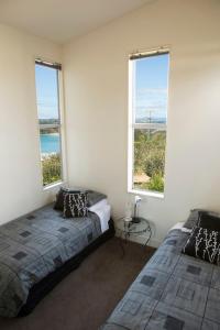 Waiheke IslandにあるView43 Beach Houseの窓が2つある部屋にベッドが2つある