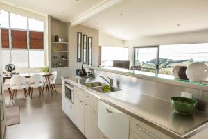 Waiheke IslandにあるView43 Beach Houseのシンクとテーブルと椅子のあるキッチン