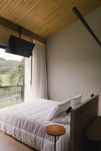 a bedroom with a large bed and a window at Elegante bangalô de campo 1- Taquaras Huts in Rancho Queimado