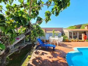 a patio with a blue chair and a table and chairs at Casa Ampla 5 quartos área lazer TOP lado Paraguai in Foz do Iguaçu
