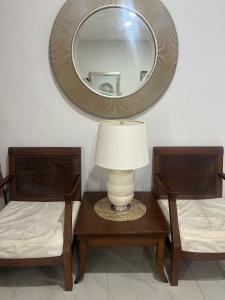 a lamp on a table with two chairs and a mirror at Villa Alyana in Ipoh +12 photos