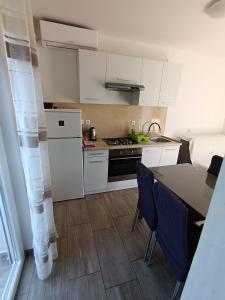 a kitchen with white cabinets and a table and chairs at Lana2 in Starigrad-Paklenica +9 photos