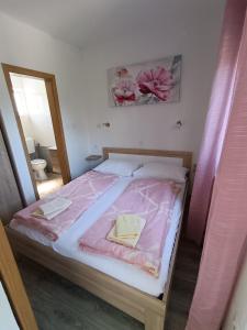 a bedroom with a bed with pink sheets and a mirror at Lana2 in Starigrad-Paklenica