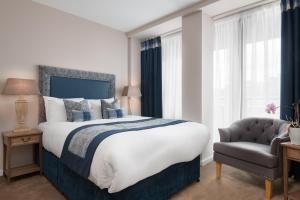 a bedroom with a large bed and a chair at Princes Street Suites in Edinburgh