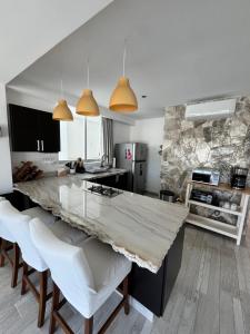 a kitchen with a large marble counter and white chairs at TERRA 1B CONDO - Nuevo Nayarit in Nuevo Vallarta