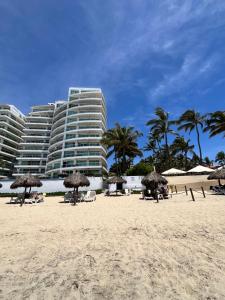 a beach with chairs and umbrellas and a large building at TERRA 1B CONDO - Nuevo Nayarit in Nuevo Vallarta