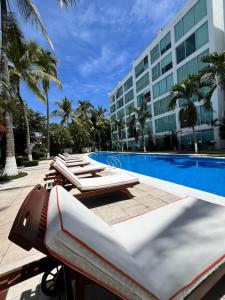 a resort pool with lounge chairs and a hotel at TERRA 1B CONDO - Nuevo Nayarit in Nuevo Vallarta