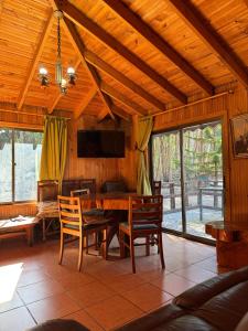 a dining room with a table and chairs and a tv at Cabaña Bosque Los Duendes in Puchuncaví