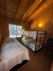 a bedroom with two beds in a wooden cabin at Cabaña Bosque Los Duendes in Puchuncaví +14 photos