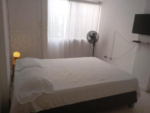 a bedroom with a white bed and a fan at @casa_grace Bienvenidos! in Cartagena de Indias