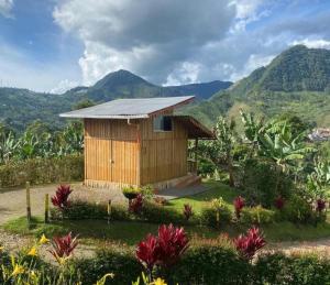 a small wooden house with mountains in the background at Cabañas Villa Juliana in Jardin