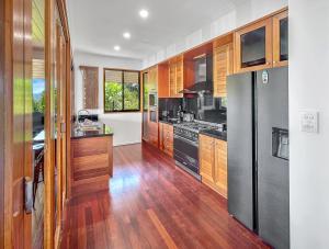 a kitchen with wooden cabinets and a black refrigerator at The Boathouse 4 Bedroom Luxury Private House in Hamilton Island
