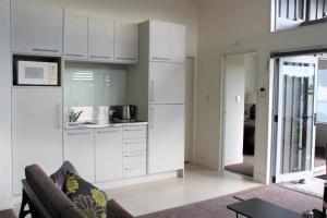 eine Küche mit weißen Schränken und einem Sofa in einem Zimmer in der Unterkunft City lights, Jewel in the Crown, Waiheke Island in Waiheke Island + 8 Fotos