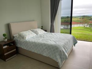 Un dormitorio con una cama y una ventana grande. en Colina Wilson, en Santa Teresa