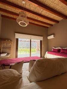 a bedroom with two beds and a large window at Moderna Cabaña en Purmamarca in Purmamarca