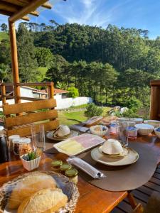 a wooden table with food on it with a view of a mountain at Mundarium - Chalés Temáticos com Hidromassagem e Cromoterapia in Santo Antônio do Pinhal