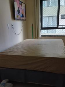 a bed in a room with a tv on the wall at Apto no D'ouro Park in Ilhéus +6 photos