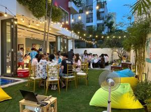 a group of people sitting at a table in a garden at Perfect Son Tra Beach Villa Da Nang with sea view in Danang