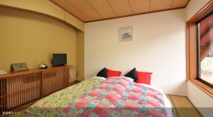 a bedroom with a bed with red pillows and a window at Tsubame Highland Lodge燕ハイランドロッジ in Myoko