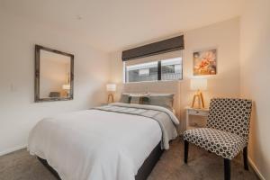 a bedroom with a bed and a chair and a mirror at Bright City Base - 1Bed Kitchen Outdoor Space in Christchurch