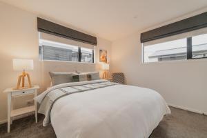 a bedroom with a white bed and two windows at Bright City Base - 1Bed Kitchen Outdoor Space in Christchurch