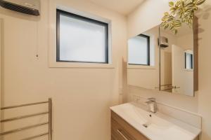 a bathroom with a sink and a mirror at Bright City Base - 1Bed Kitchen Outdoor Space in Christchurch +26 photos
