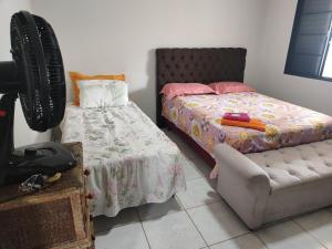 a bedroom with a bed and a chair and a fan at Suite tripla Pousada Canto dos Pássaros in Cianorte +1 photo
