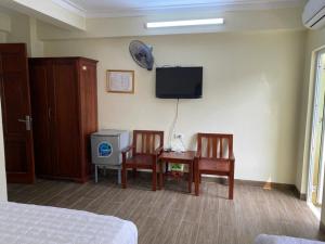 a bedroom with two chairs and a table and a tv at Hoa Lư Hotel in Sầm Sơn