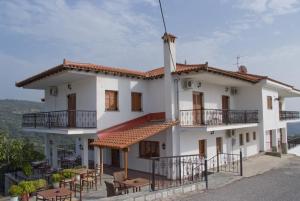 un gran edificio blanco con mesas y sillas en Guesthouse Arsenis, en Kalambaka