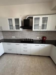 a kitchen with white cabinets and a black counter top at Poonam apartments 2 in Prayagraj