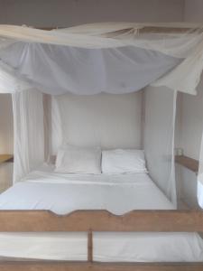 un letto bianco con lenzuola e cuscini bianchi di Hostel Mata House Nova Caraíva a Porto Seguro