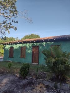 una casa verde con una porta marrone in un cortile di Hostel Mata House Nova Caraíva a Porto Seguro
