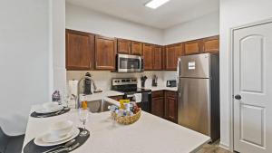 a kitchen with wooden cabinets and a stainless steel refrigerator at Stunning 1bd Apartment I Frisco near Dallas I Pool, Gym, Work Space in Frisco