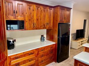 a kitchen with wooden cabinets and a black refrigerator at Miners' cottage in Broken Hill +13 photos