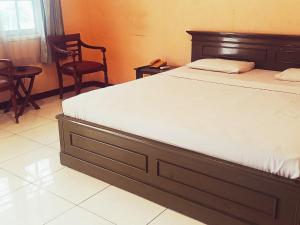 a bedroom with a bed with a wooden frame and chairs at Hotel Wijaya Purwokerto in Purwokerto +77 photos