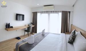 a bedroom with a large white bed and a desk at Remember Vangvieng Hotel in Vang Vieng