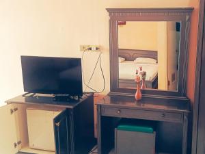 a bedroom with a desk with a mirror and a television at Hotel Wijaya Purwokerto in Purwokerto