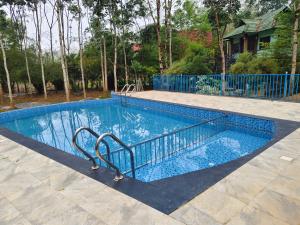 a swimming pool with a blue fence around it at River Valley Huts, Wayanad in Panamaram