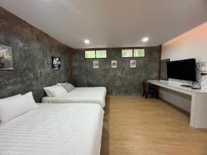 a bedroom with two beds and a desk with a television at maksaihomestay in Ban Lo Pa Ret