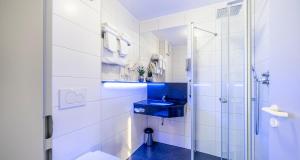 a bathroom with a blue sink and a shower at PLAZA INN Braunschweig City Süd in Braunschweig
