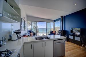 a kitchen with a sink and a view of the ocean at Battery Cove Beach Front Apartment in Port Fairy